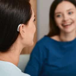 Younger woman with hearing aid talking to her friend.