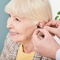 Happy senior woman getting fitted with a hearing aid by her audiologist.