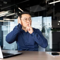 Person in office shushing a loud noise, covering his ear