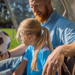 Young girl plays soccer with hearing aid