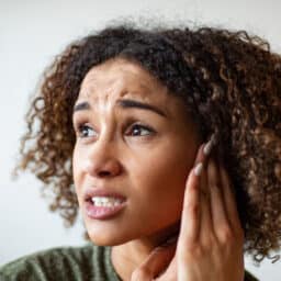 Woman with tinnitus holding her ear