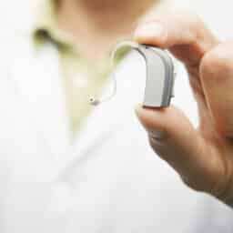 Close-up of a provider holding up a hearing aid