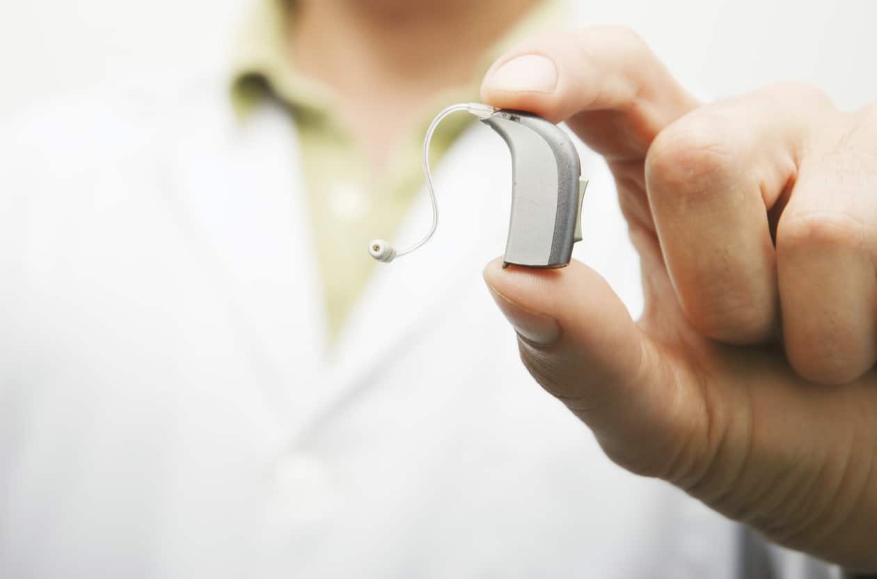 Close-up of a provider holding up a hearing aid.