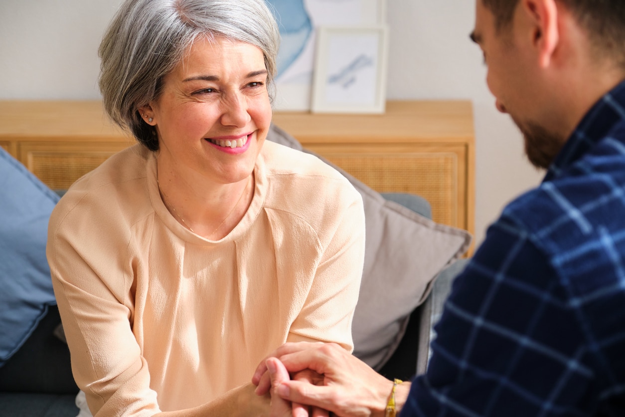 Man talking to his mom, holding her hand.
