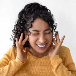 Woman with tinnitus holding her ears.