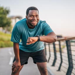Smiling man checking his smart watch on an outdoor run.