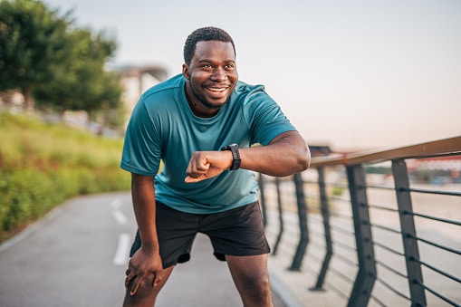 Smiling man checking his smart watch on an outdoor run.
