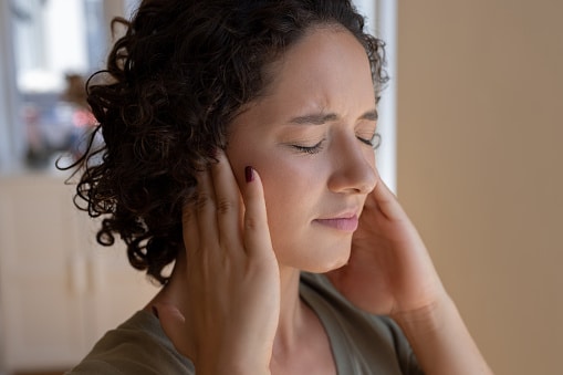 Woman covering her ears, trying to block out tinnitus.